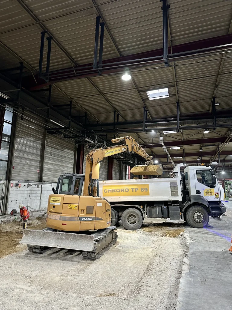 Camion-benne Chrono TP 89 et pelle sur un chantier de réseaux en intérieur