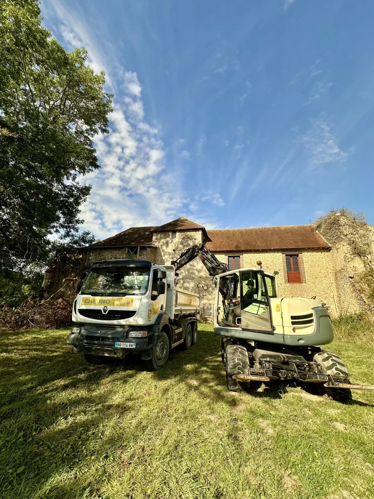 Camion-benne et pelle devant une longère en travaux