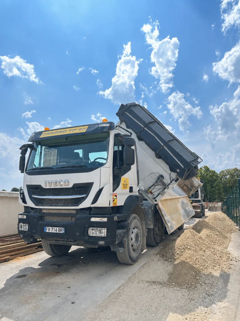 Camion-benne Iveco déchargeant du gravier sur un chantier